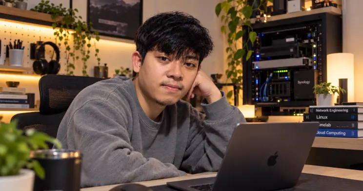Portrait of Listiananda Apriliawan against a blue illustrated background of coding doodles